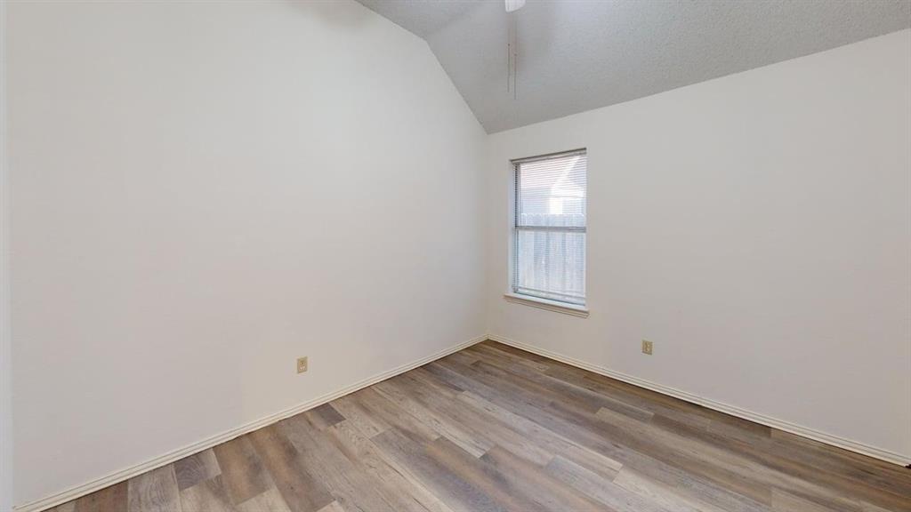 Room featuring vaulted ceilings, wood-finish flooring, and a single-pane window Room featuring vaulted ceilings, wood-finish flooring, and a single-pane window