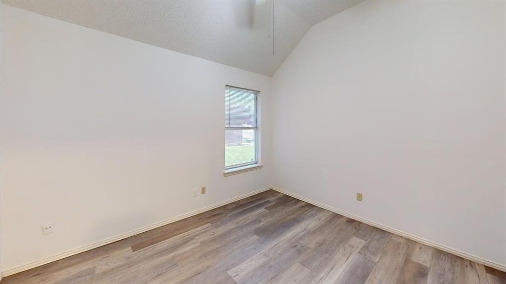 Room with vaulted ceilings, wood-finish flooring, and single-pane window with blinds Room with vaulted ceilings, wood-finish flooring, and single-pane window with blinds