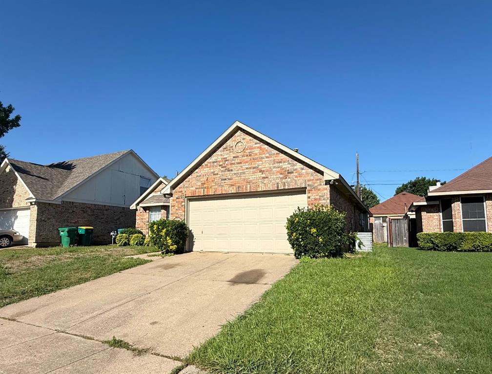 Brick exterior featuring a gabled roofline, concrete driveway, and attached two-car garage