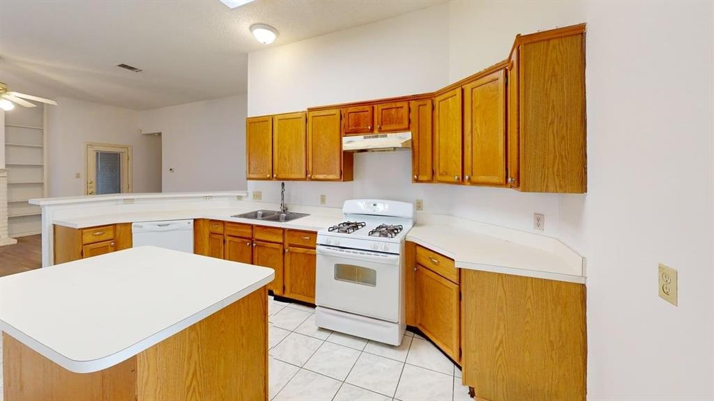 Kitchen featuring wood cabinetry, white countertops, a central island, a white gas range with overhead vent hood, and tile flooring