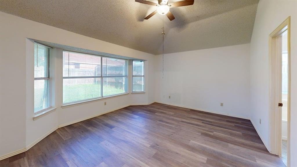 Room featuring a vaulted ceiling, wood-finish flooring, and a bay window Room featuring a vaulted ceiling, wood-finish flooring, and a bay window