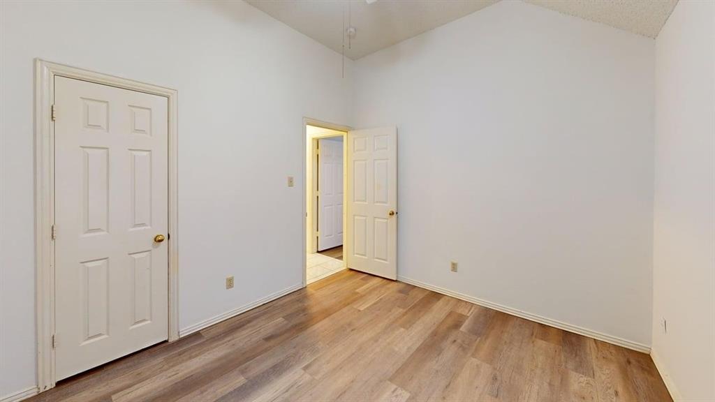 Interior room featuring vaulted ceilings, wood-finish flooring, and six-panel doors Interior room featuring vaulted ceilings, wood-finish flooring, and six-panel doors