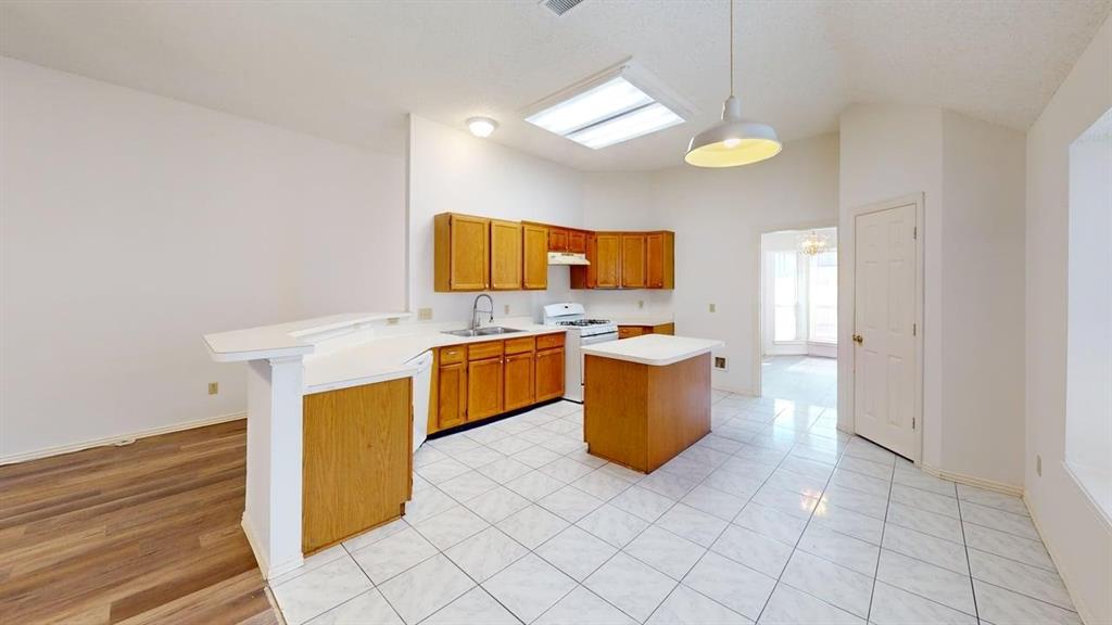 Kitchen featuring wood cabinetry, white countertops, a central island, tile flooring, and recessed ceiling lighting