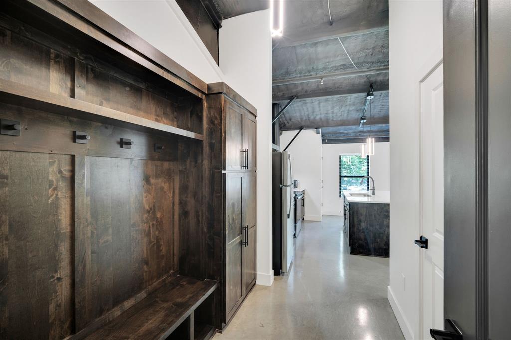 Custom floor-to-ceiling wood cabinetry, polished concrete flooring, exposed industrial ceiling, and matte black hardware