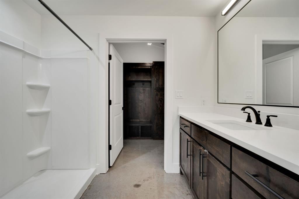 Bathroom featuring a vanity with dark-stained cabinetry, a solid-surface countertop, and a widespread matte black faucet