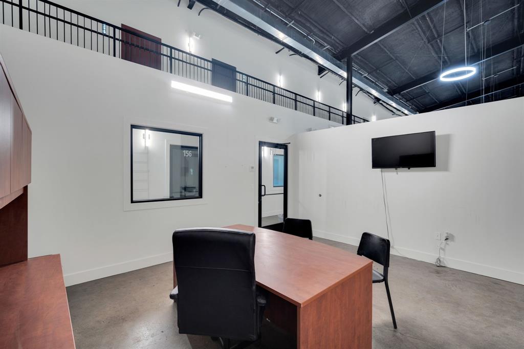 Industrial-style interior featuring high ceilings with exposed structural elements, concrete flooring, a mezzanine level with black metal railings, and integrated circular lighting fixtures