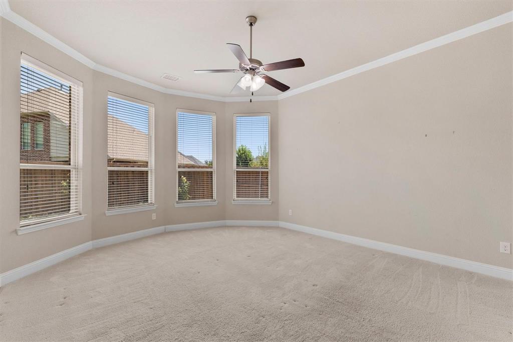 Bay window architecture featuring four windows, neutral carpeting, crown molding, and a central ceiling fan with integrated lighting