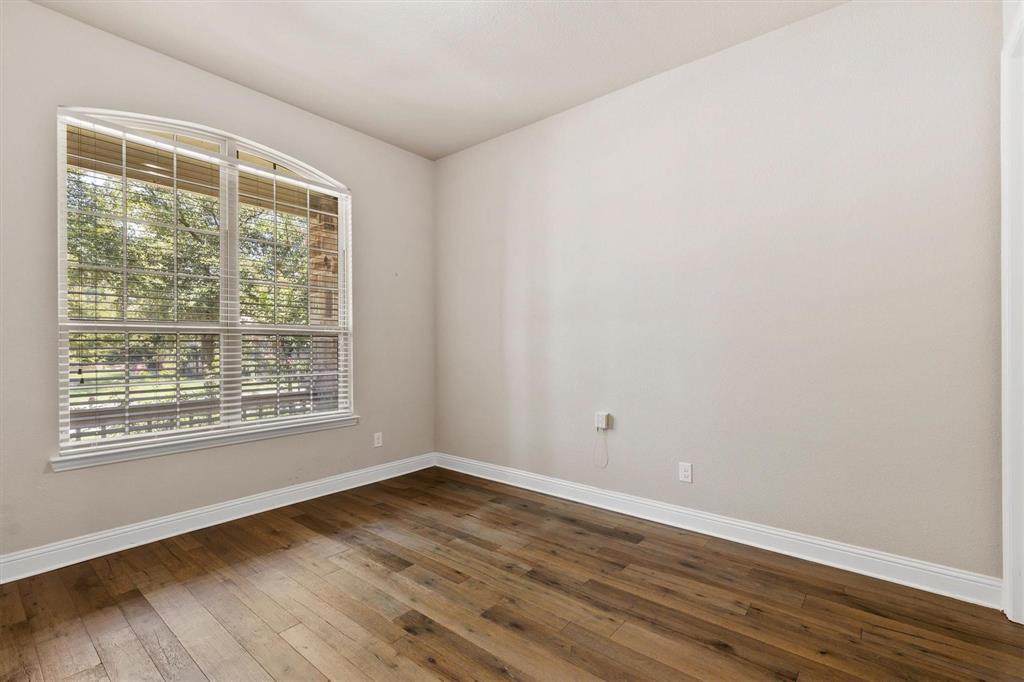 Room featuring arched window, wood-finish flooring, and neutral wall tones