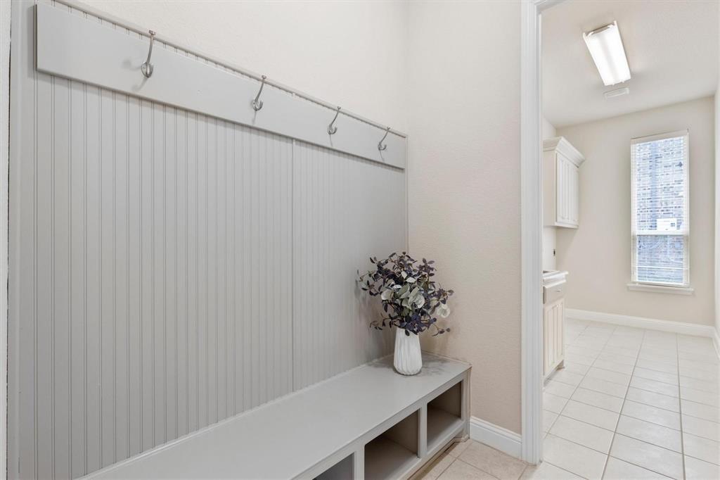 Built-in mudroom bench featuring beadboard paneling, integrated coat hooks, and open lower storage cubbies