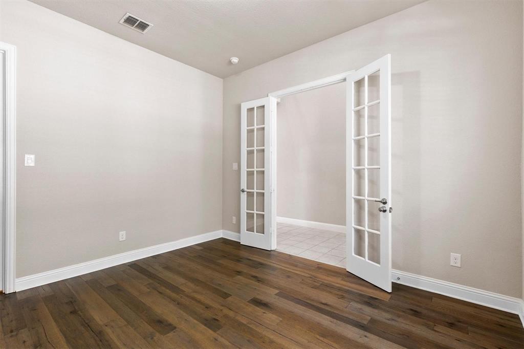 Interior room featuring wood-finish flooring, neutral wall tones, and white-framed French doors