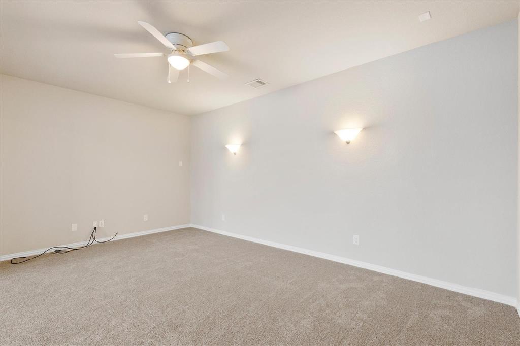 Neutral-toned carpeting, white wall-mounted sconce lighting, and a central ceiling fan with integrated lighting