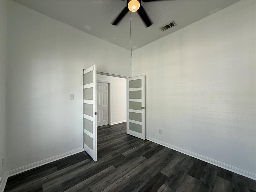 Room featuring vaulted ceilings, wood-finish flooring, and dual French doors with frosted glass inserts, complemented by a ceiling fan