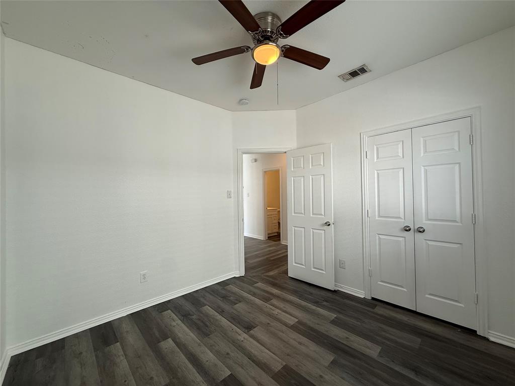 Wood-finish flooring, ceiling fan with integrated lighting, and closet with white paneled double doors