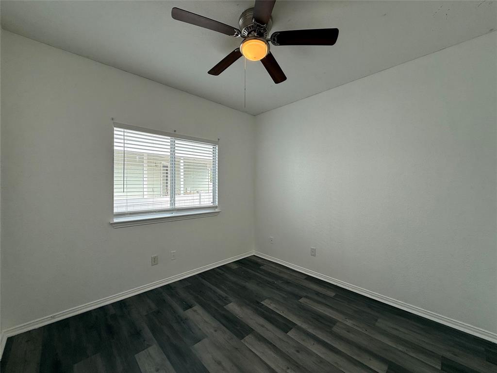 Wood-finish flooring, multi-pane window with horizontal blinds, and ceiling fan with integrated light fixture