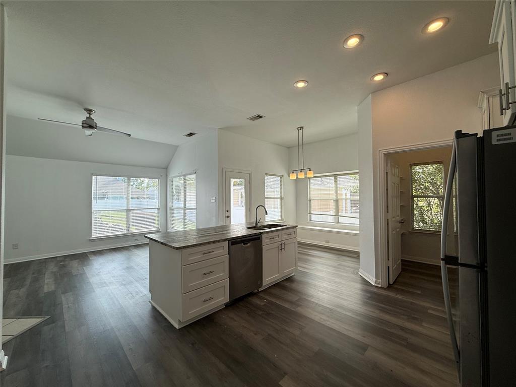 Kitchen featuring a central island with a stone-finish countertop, white cabinetry, recessed lighting, wood-finish flooring, and a vaulted ceiling