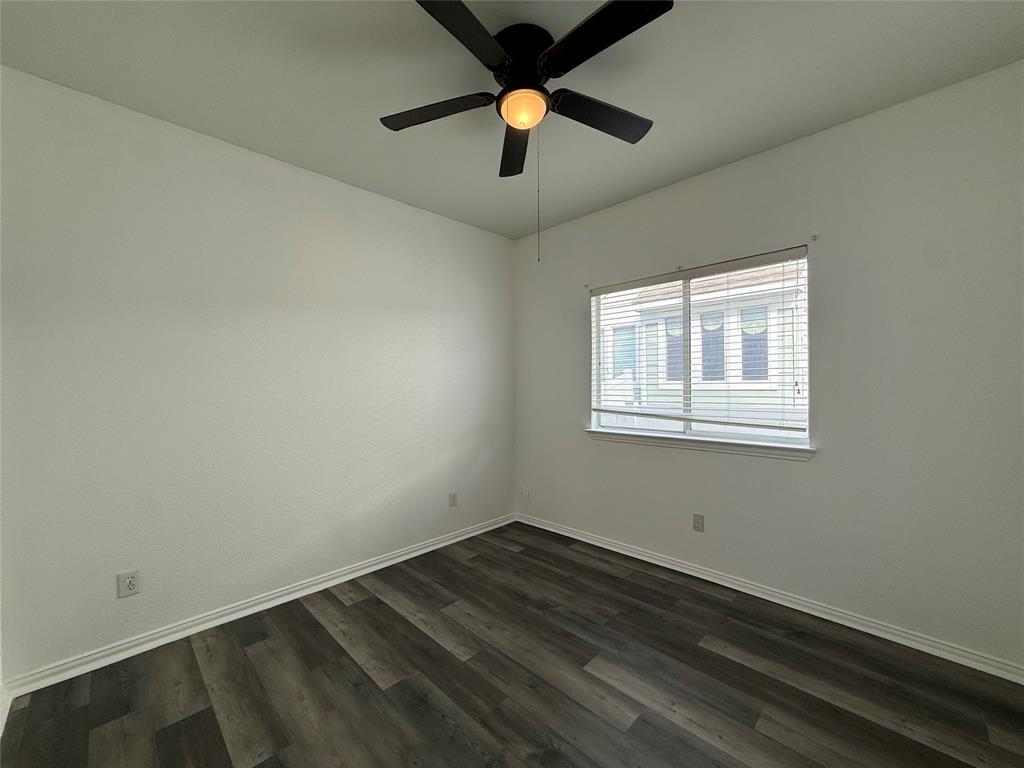 Wood-finish flooring, neutral walls, sliding window with blinds, and ceiling fan with integrated light fixture