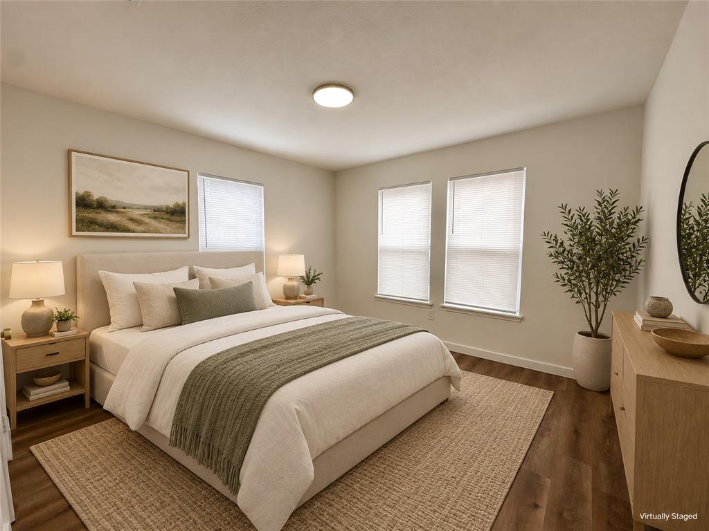 Neutral-toned walls, wood-finish flooring, two dual-pane windows with fitted blinds, and a circular flush-mount ceiling light