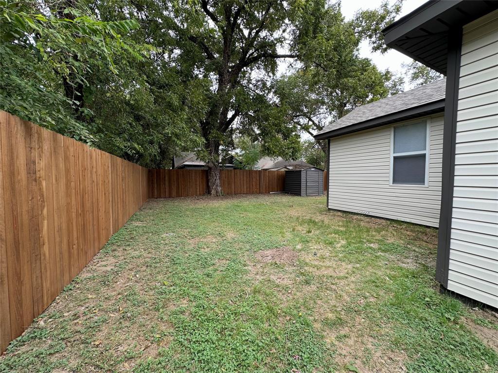 Backyard space featuring a horizontal wood privacy fence, vinyl siding exterior, and mature trees