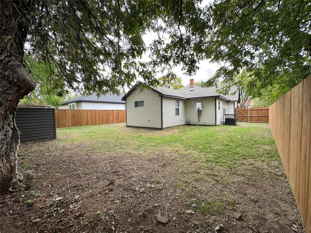 Rear exterior featuring light-colored horizontal siding, wood-style privacy fencing, and a detached storage structure