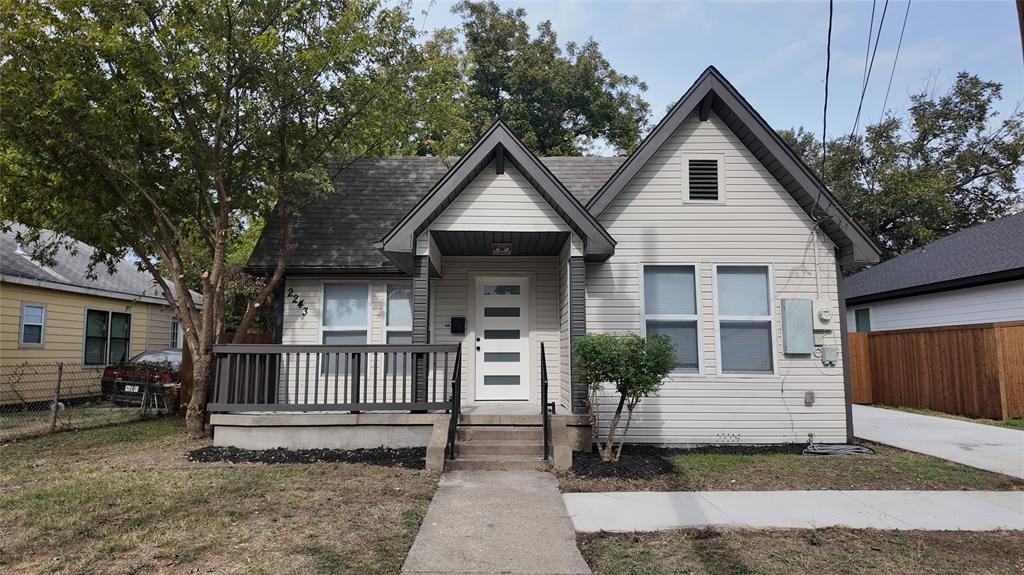 Exterior facade featuring horizontal siding, a gabled roofline, covered front porch with dark railings, and a multi-lite front door