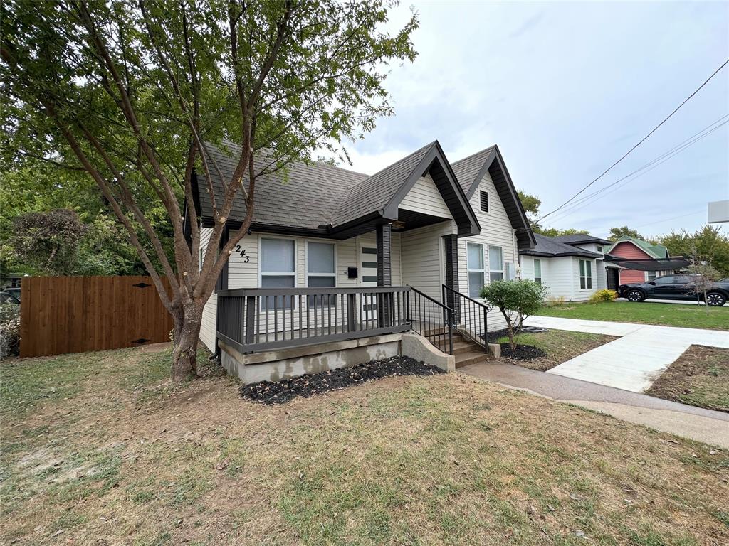 Exterior featuring light-toned horizontal siding, dual-gabled roofline, covered front porch with a dark railing, and a concrete driveway Exterior featuring light-toned horizontal siding, dual-gabled roofline, covered front porch with a dark railing, and a concrete driveway
