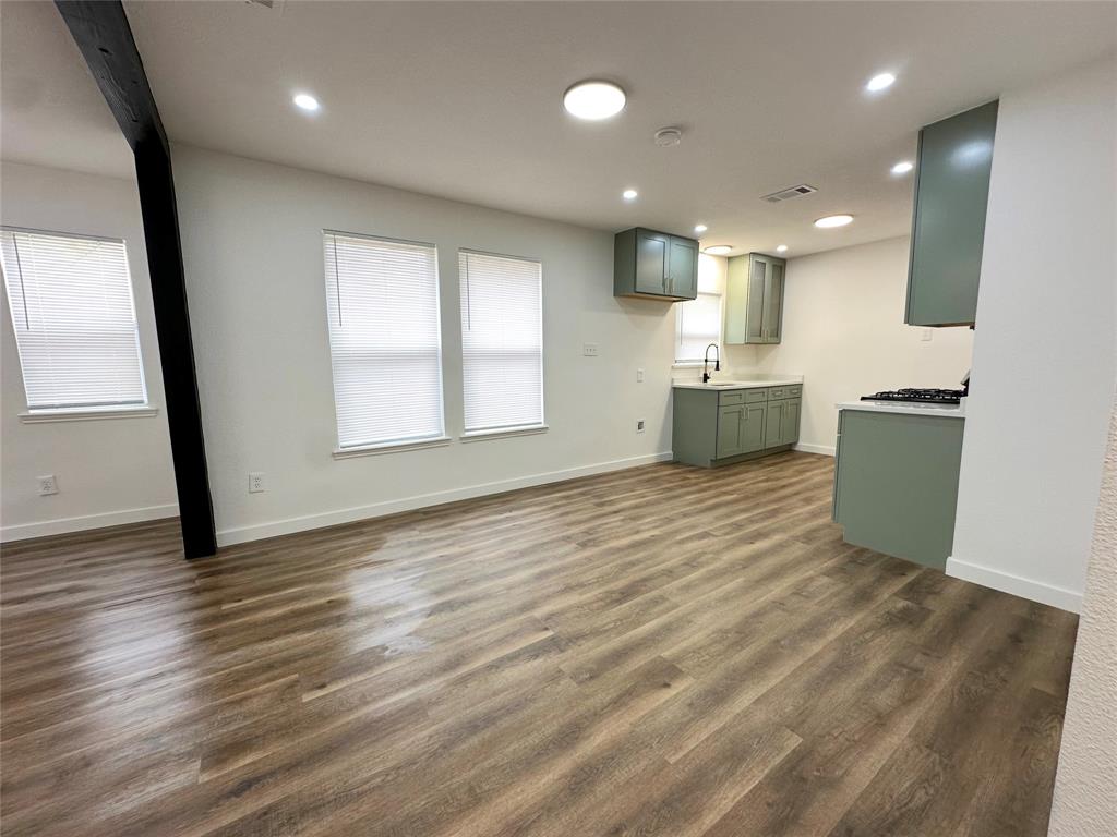 Open-concept space featuring wood-finish flooring, recessed lighting, a structural beam, sage-toned cabinetry, and a gas range