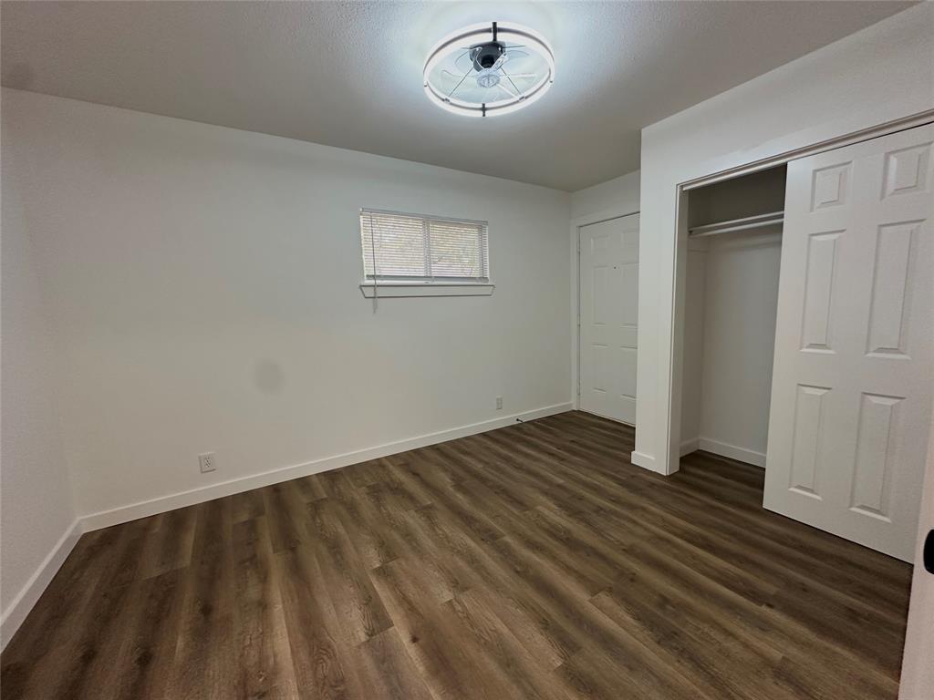 Wood-finish flooring, crisp white walls, sliding closet door, and contemporary circular ceiling light fixture