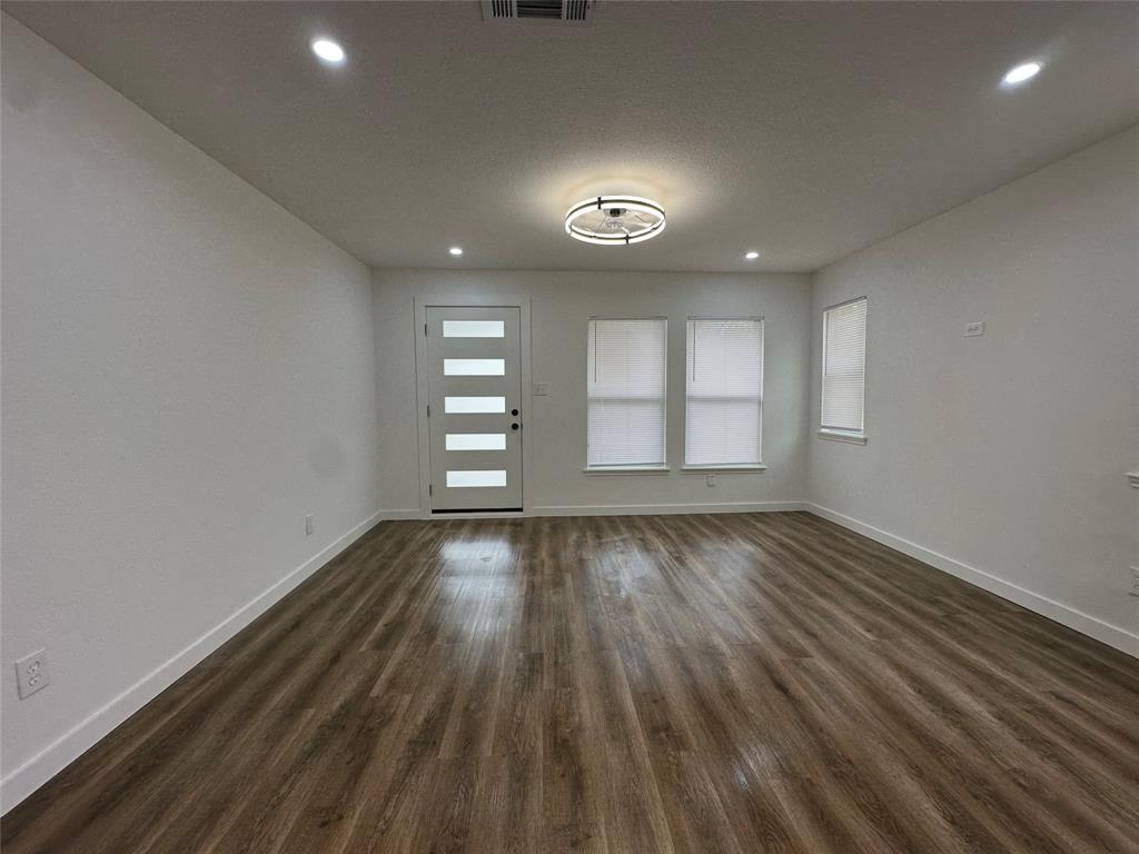 Interior featuring wood-finish flooring, recessed lighting, a modern central light fixture, and a multi-panel glass-inset entry door