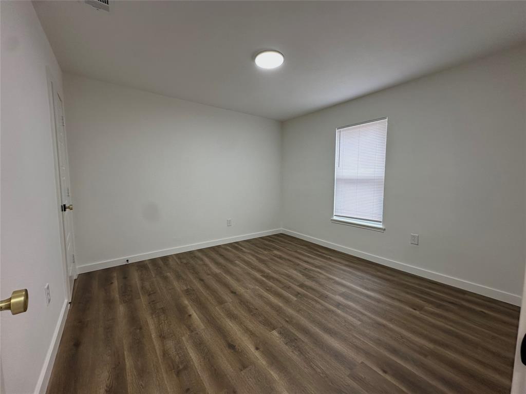 Room featuring wood-finish flooring, neutral wall paint, and a single-pane window with installed blinds