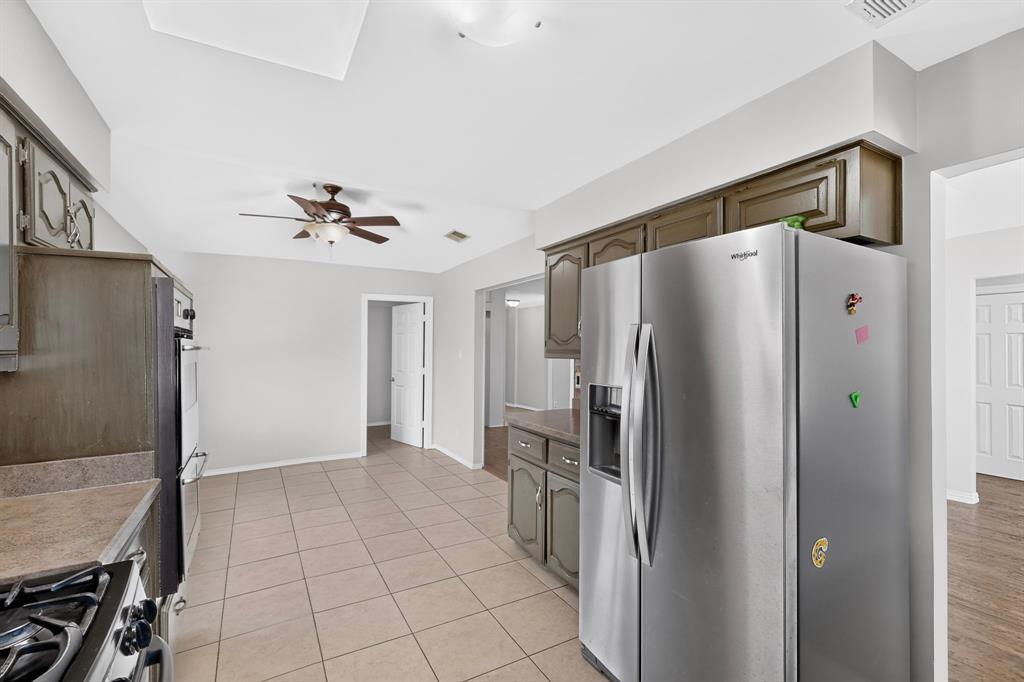 Kitchen featuring ceramic tile flooring, upper and lower cabinetry, stainless steel refrigerator, and recessed ceiling