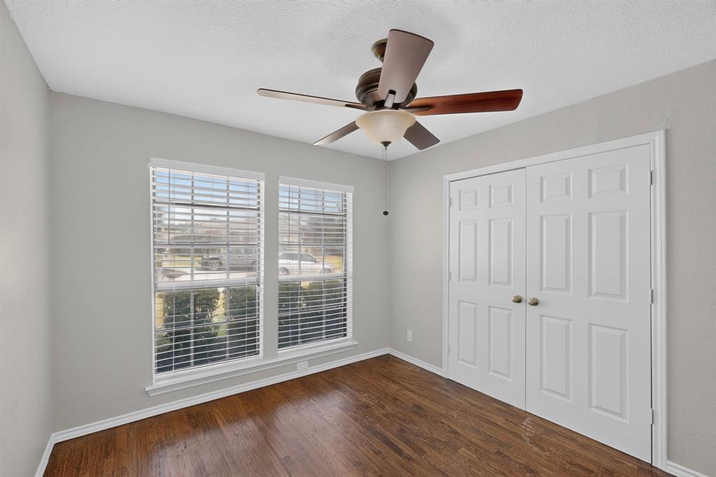 Hardwood-finish flooring, dual windows with blinds, bi-fold closet doors, and a ceiling fan with integrated lighting