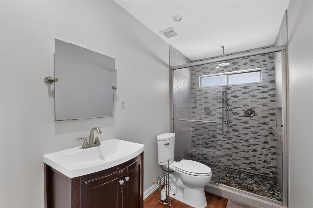 Glass-enclosed shower with mosaic tile surround and river rock base
