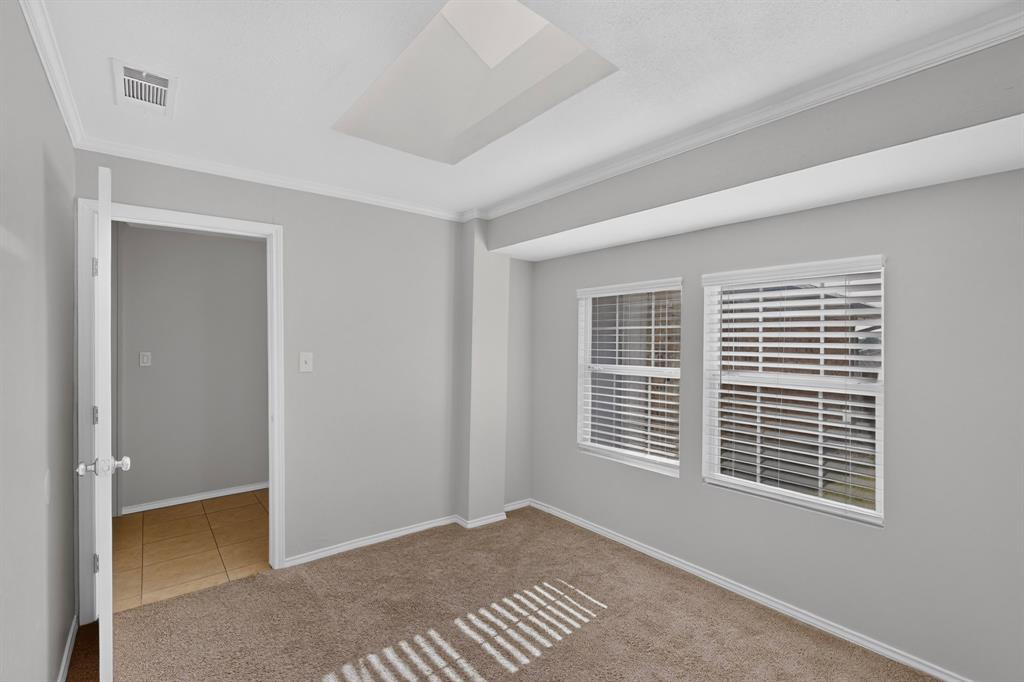 adjoining study Recessed ceiling light, crown molding, two windows with blinds, light-colored carpeting, and a doorway to a tiled space