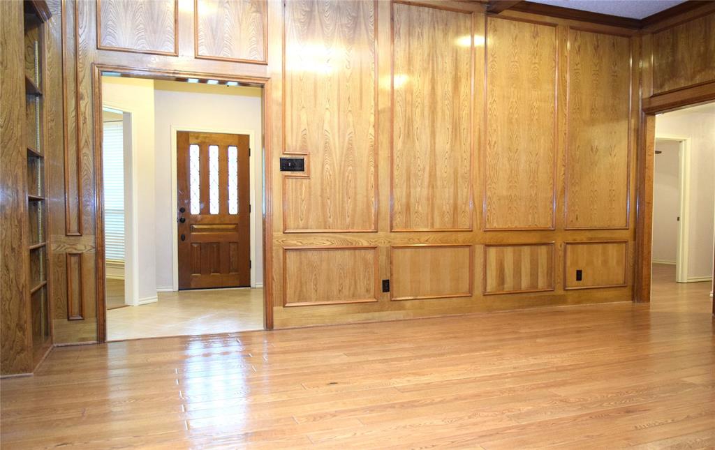 Full-height wood paneling with decorative trim, built-in floor-to-ceiling shelving, and wood-finish flooring