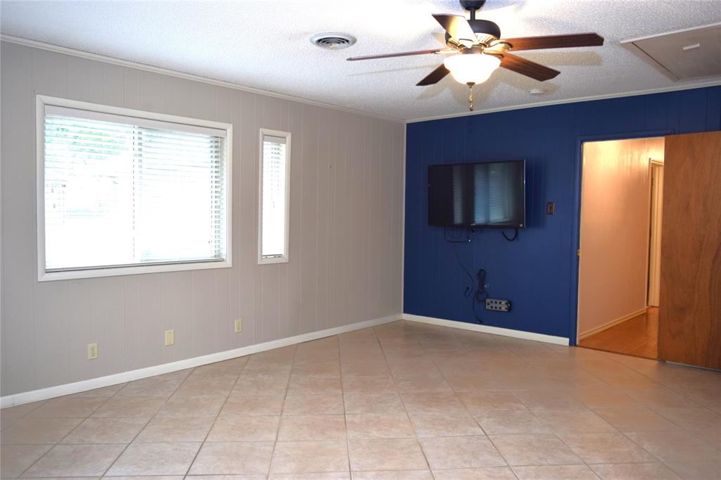 Living area featuring tile flooring, ceiling fan with integrated lighting, and dual windows