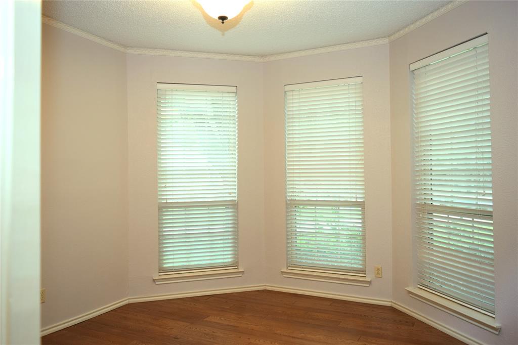 Bay window featuring three rectangular windows, wood-finish flooring, crown molding, and a central ceiling-mounted light fixture