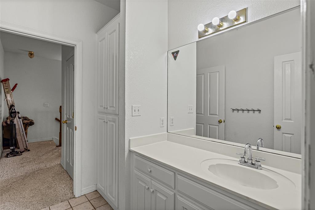 Full-width wall mirror, vanity with integrated sink, three-light fixture, and built-in floor-to-ceiling cabinetry