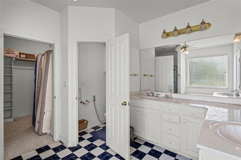 Double vanity with a stone countertop, white cabinetry, a large wall-mounted mirror, and black and white checkerboard tile flooring