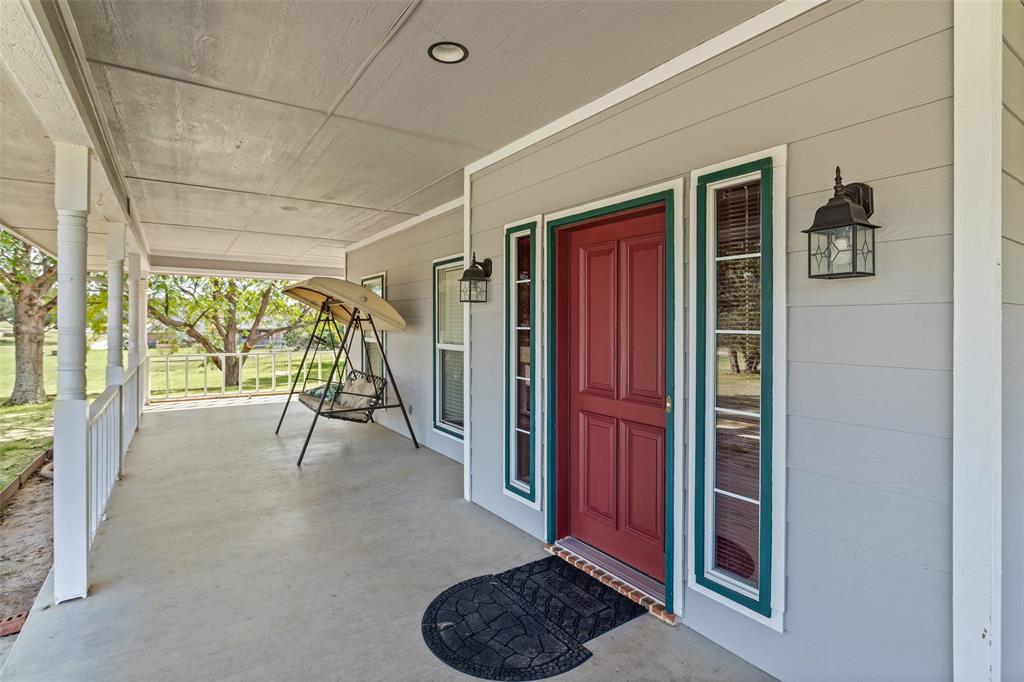 Covered front porch featuring lap siding, paneled front door with sidelights, and exterior wall-mounted lanterns