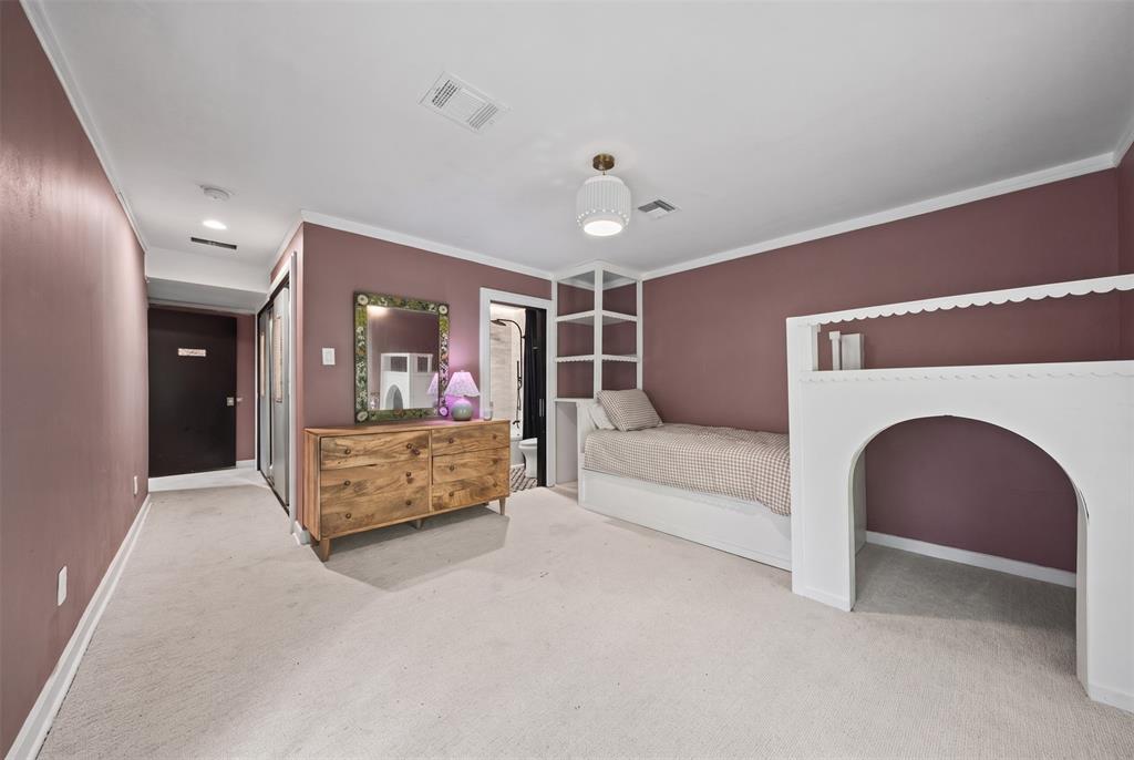 Room featuring neutral carpeting, recessed ceiling lighting, a pendant light fixture, and custom built-in white millwork with integrated shelving and an arched structural element