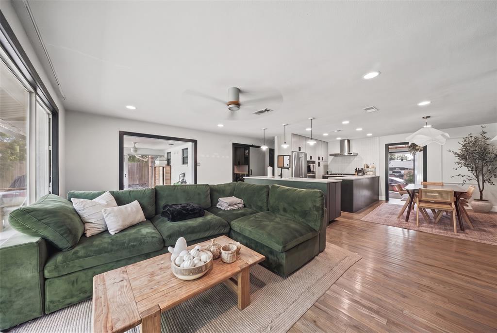 Open-concept interior featuring wood-finish flooring, recessed lighting, a modern ceiling fan, and a kitchen equipped with a central island and stainless steel range hood
