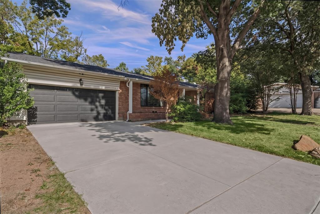 Single-story residence featuring a brick and horizontal siding exterior, a concrete driveway, a multi-car garage, and mature trees
