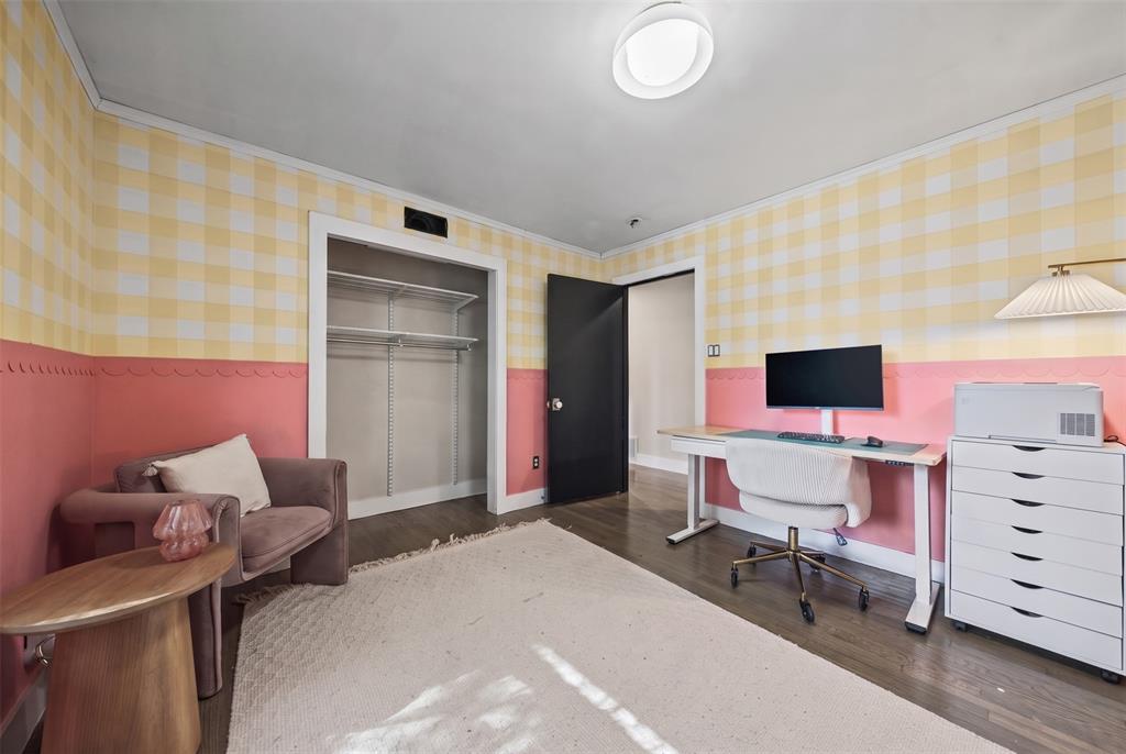 Room featuring wood-finish flooring, a reach-in closet with built-in shelving, and a dual-tone wall treatment