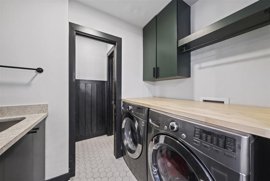 Utility room featuring wood-finish countertop, deep-toned wall-mounted cabinetry, integrated hanging rail, stone-finish sink deck, and hexagon floor tiling