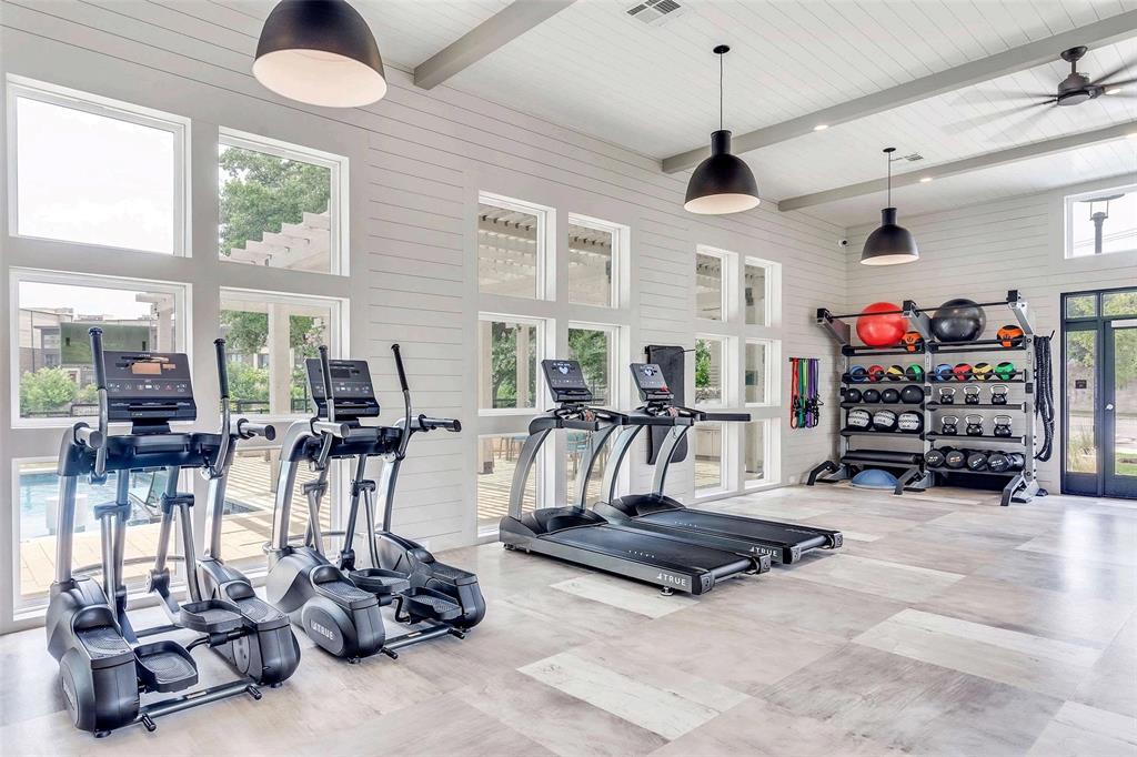 Workout area with beamed ceiling, a towering ceiling, french doors, wood walls, and ceiling fan