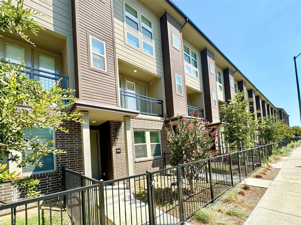 Multi-level exterior featuring dark brick and horizontal siding, private balconies with metal railings, and a fenced front entry