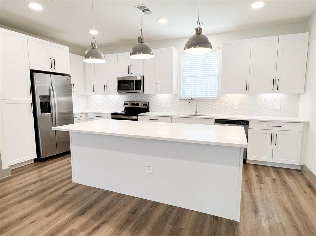 Kitchen featuring a kitchen island, hanging light fixtures, white cabinets, appliances with stainless steel finishes, and recessed lighting Kitchen featuring a kitchen island, hanging light fixtures, white cabinets, appliances with stainless steel finishes, and recessed lighting
