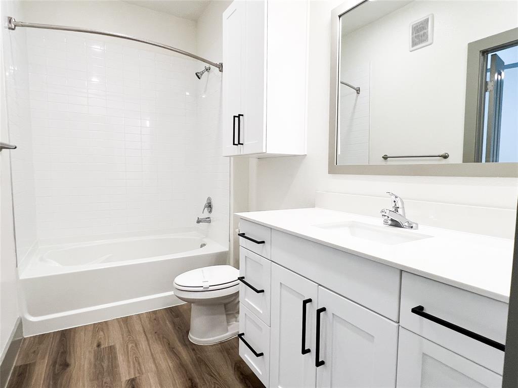 Bathroom featuring dark wood-type flooring, vanity, and shower / bath combination