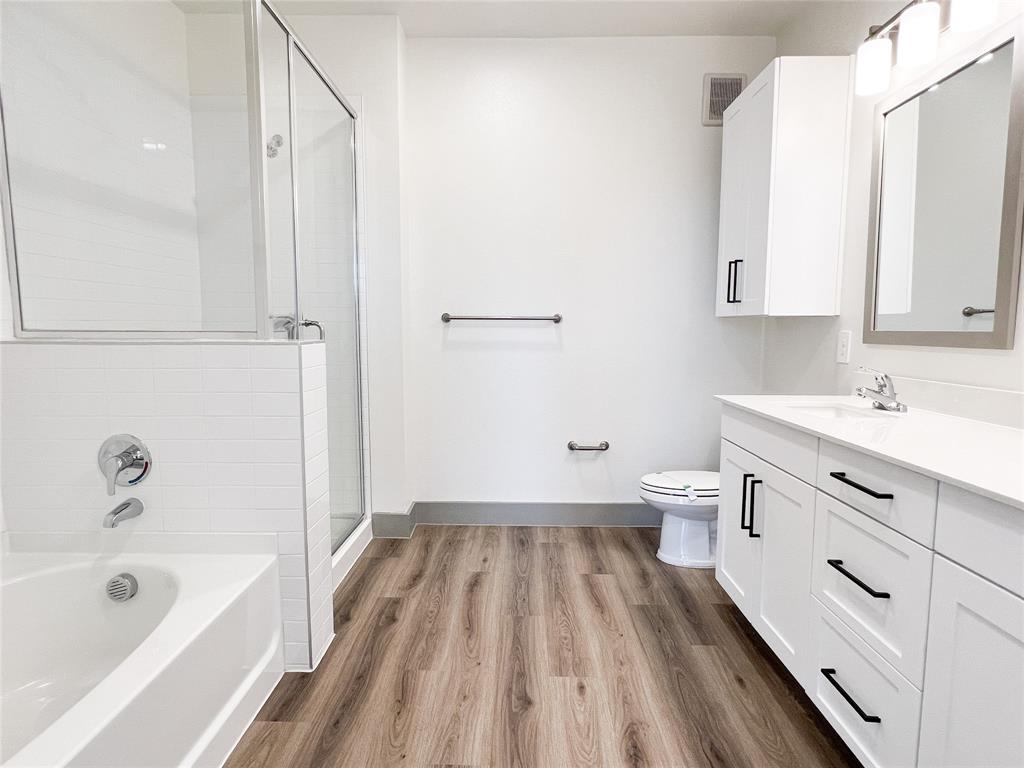 Full bath featuring a bath, vanity, a stall shower, and light wood-style floors
