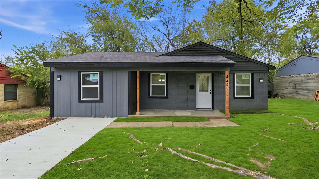 Single-story exterior featuring painted brick and vertical siding, a covered front porch with natural wood support posts, and a concrete driveway